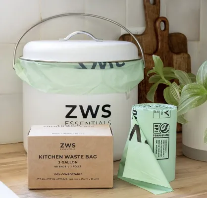 This image depicts a set of materials to help someone start their zero waste journey: a countertop compost bin and a box of compost bin liners