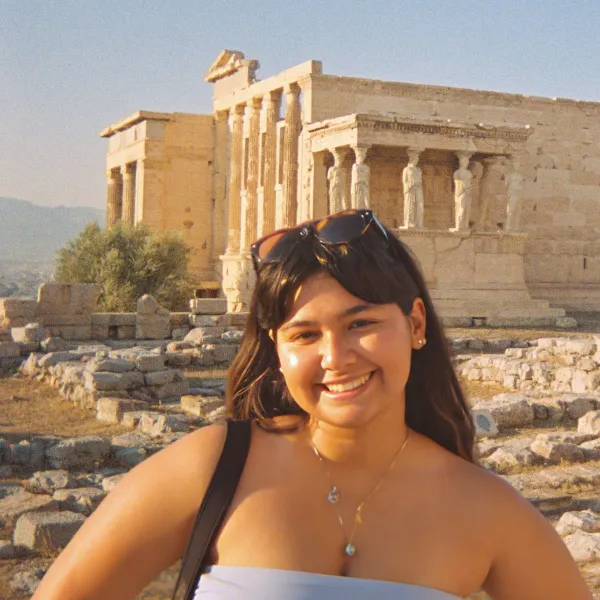 Female student stands smiling in front of the Parthanon.