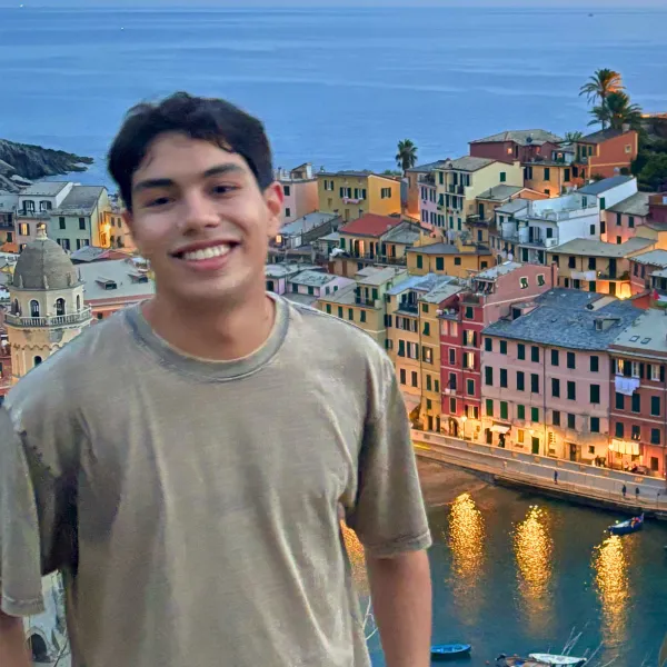 Male student stands in foreground of Italian city skyline