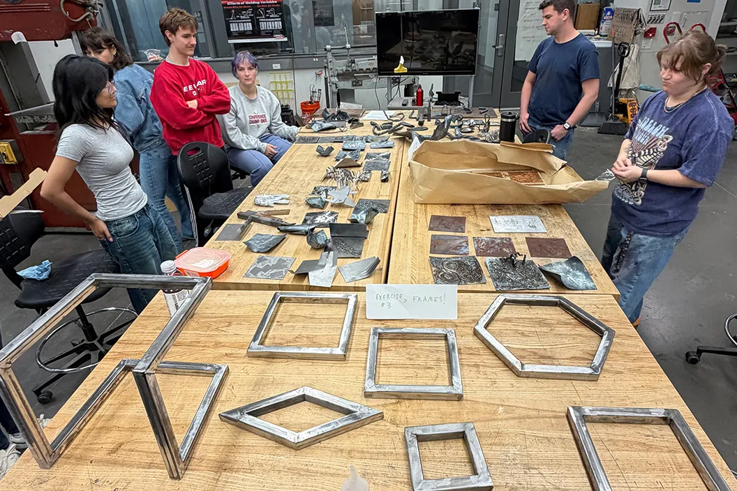 Welding class students with metalwork on table