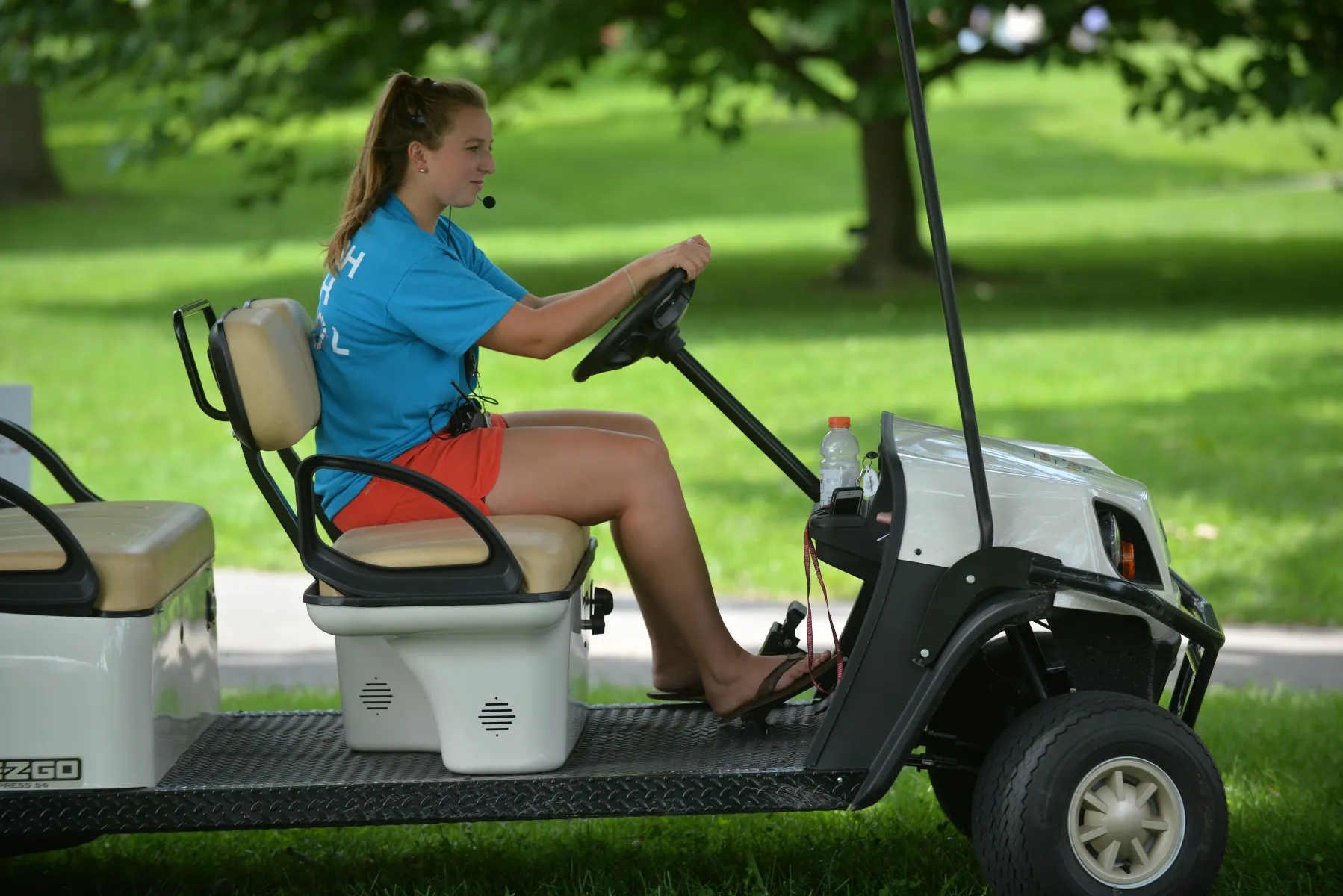 A student work drives a golf cart
