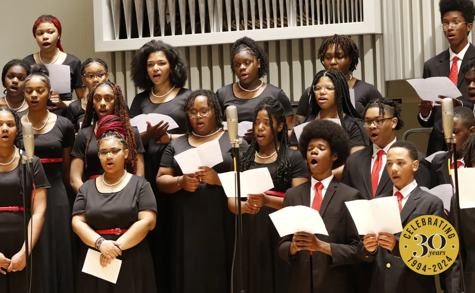 children in black dresses and suit jackets singing in chorus with the Chester Children's Chorus