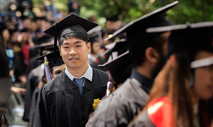 A student looks out from a line of graduates at Commencement