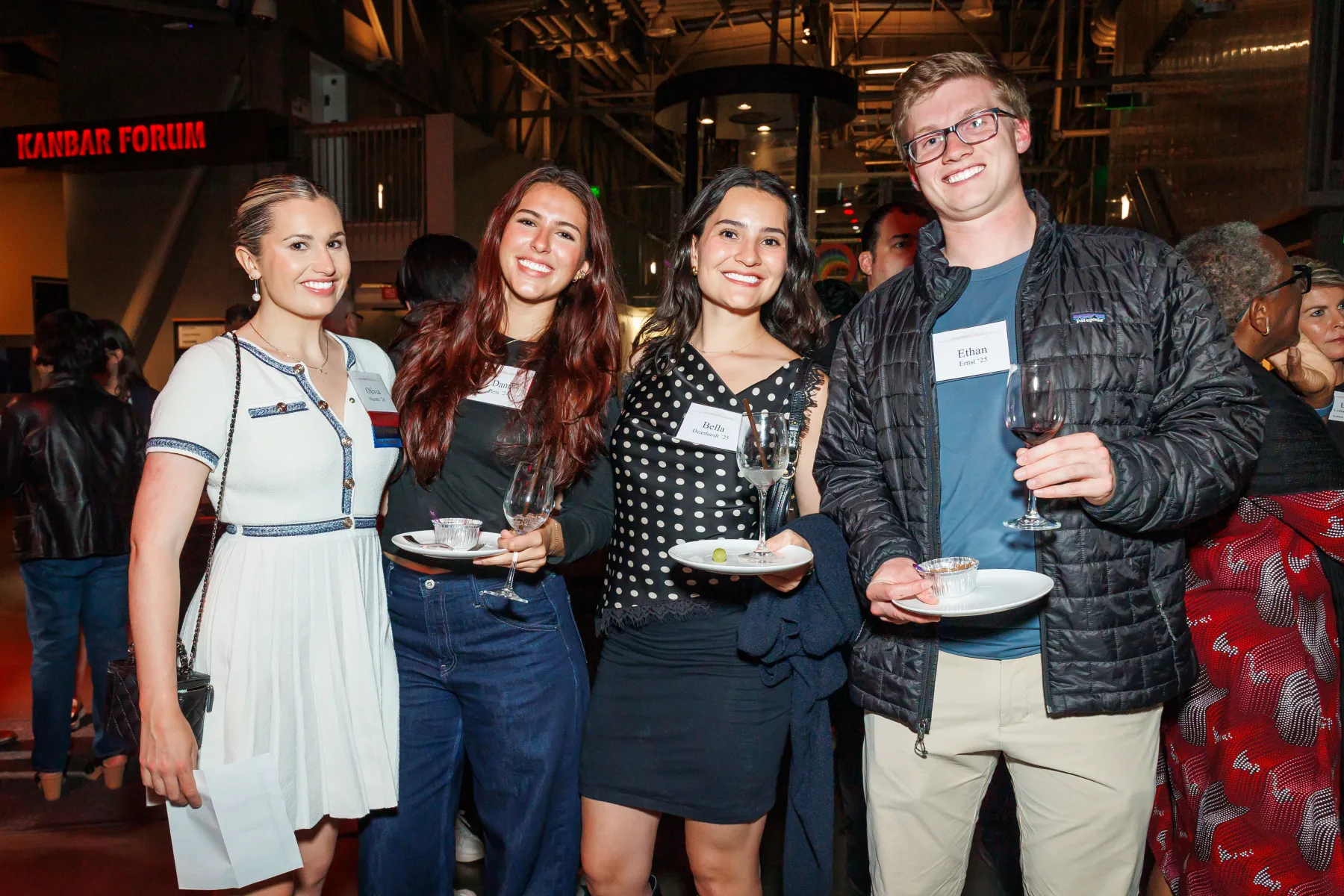 A group of young alumni pose, smiling, at a College event