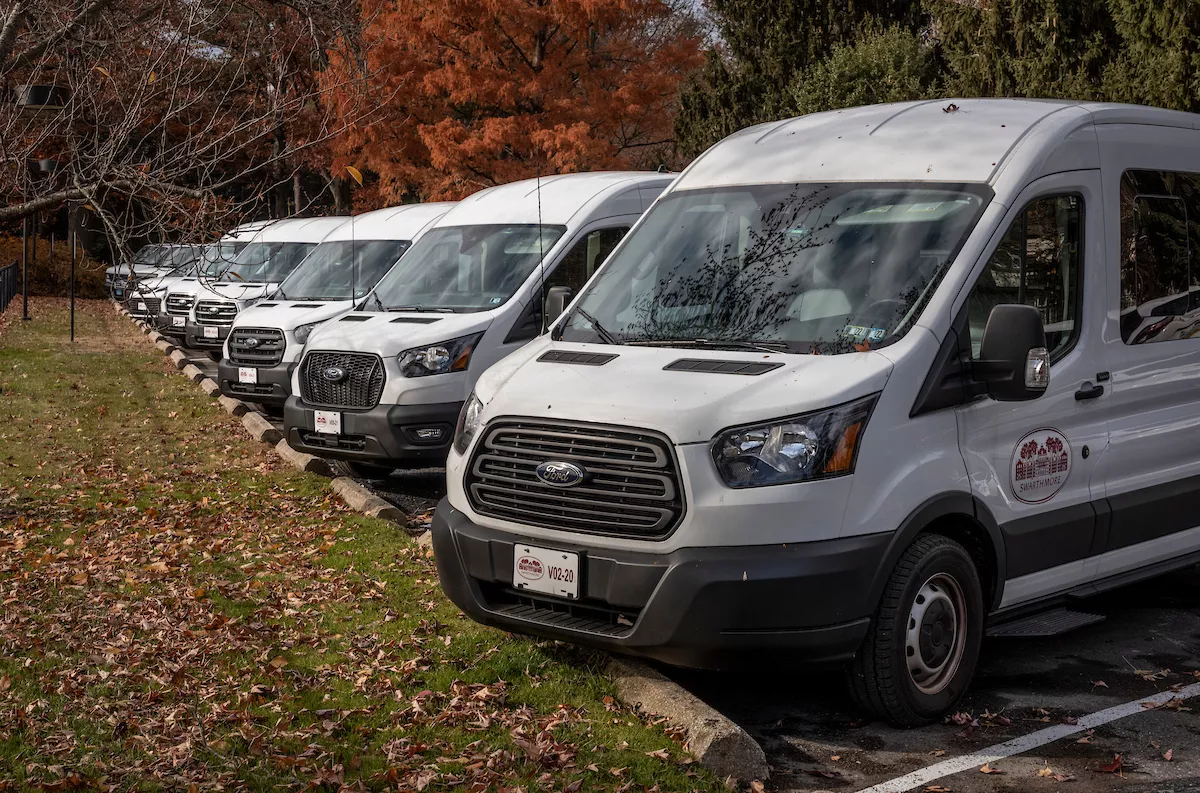 Row of white vans with Swarthmore College logo parked next to one another