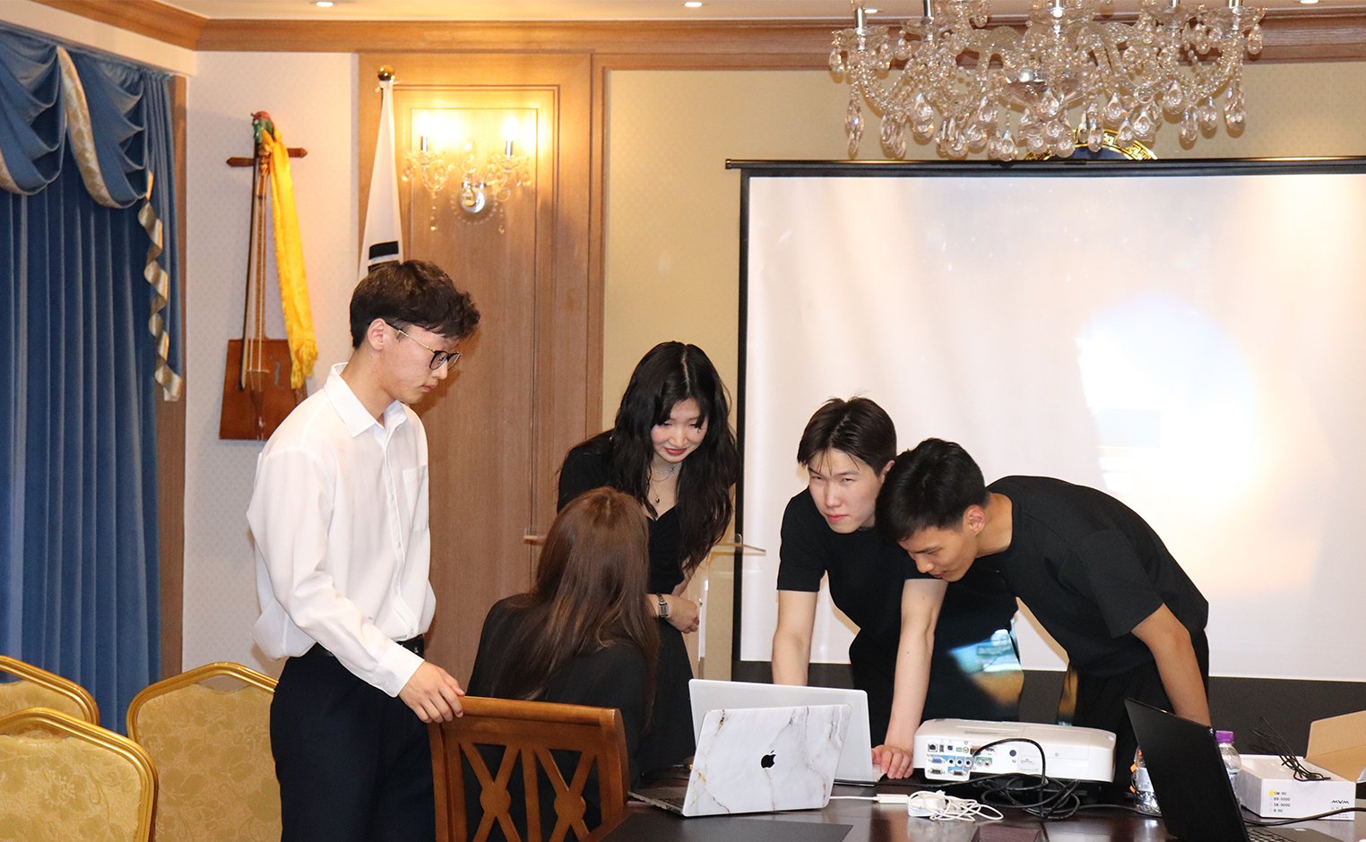 A group of students look at a computer attached to a projector.