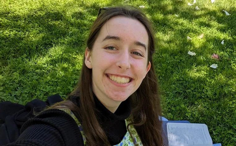 Elsa Toland sitting on the grass with a book nearby