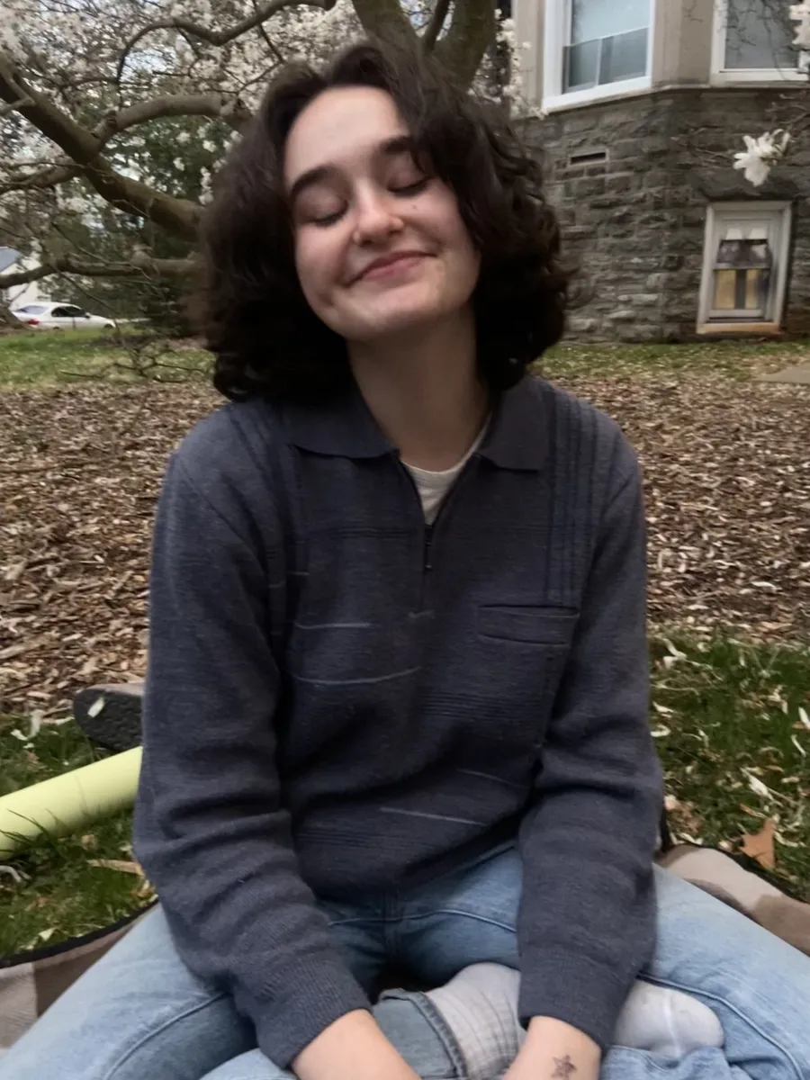 Julia Stern sitting cross legged on the ground outdoors on campus