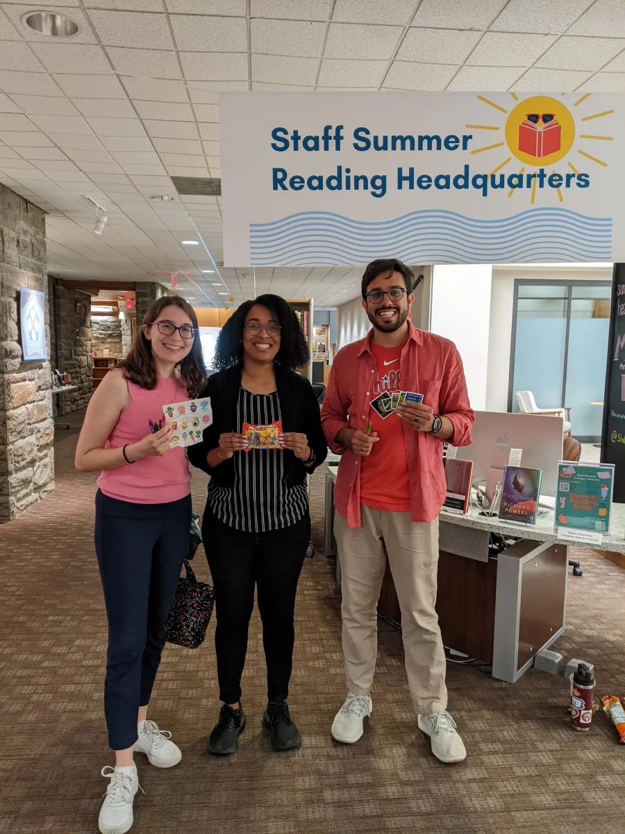 3 staff members standing in McCabe Library at the Summer Reading Desk