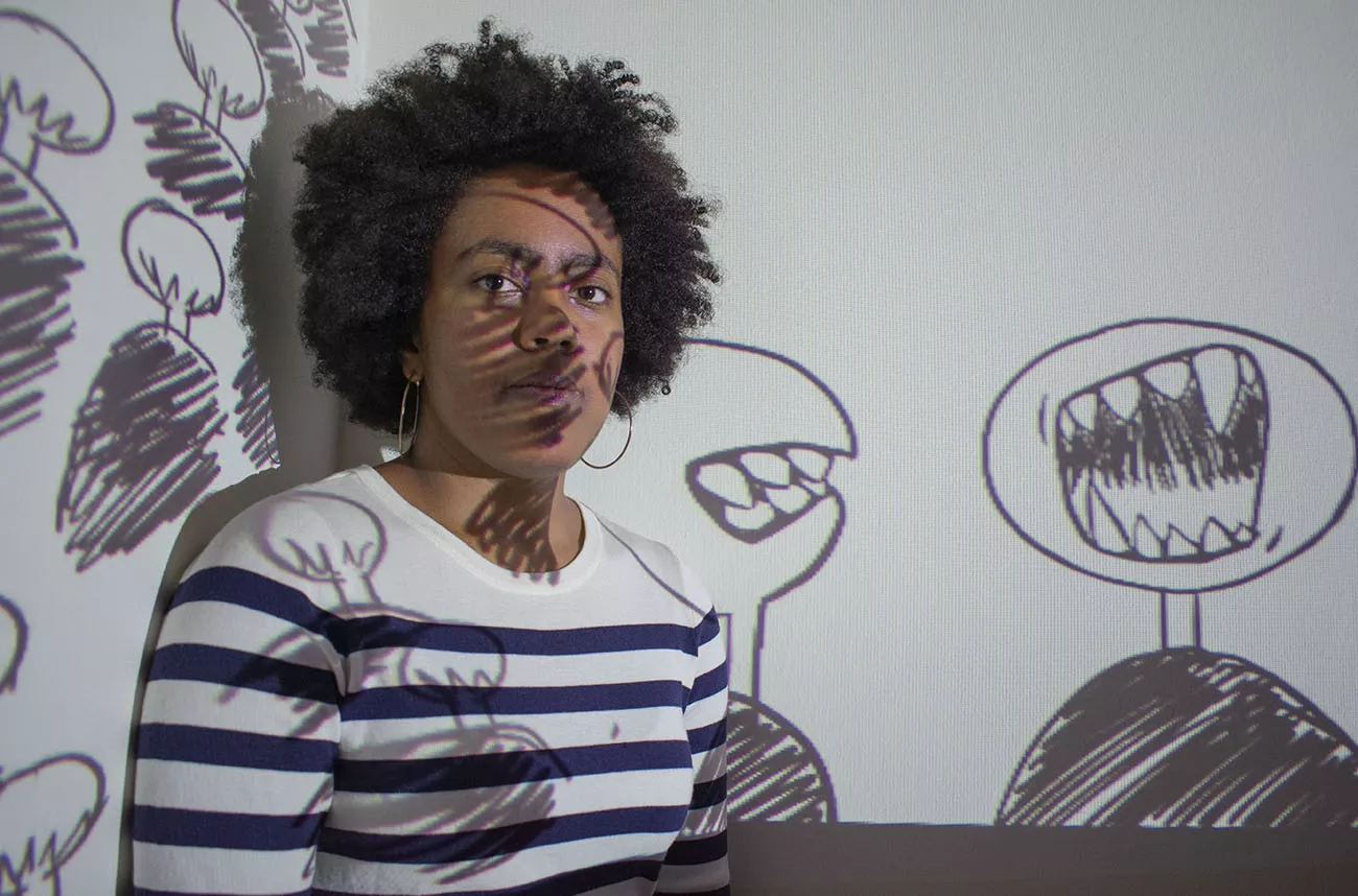 student artist in front of screen with drawings