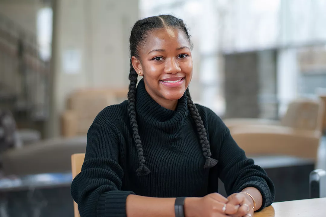 Student wears black sweater and sits at table indoors