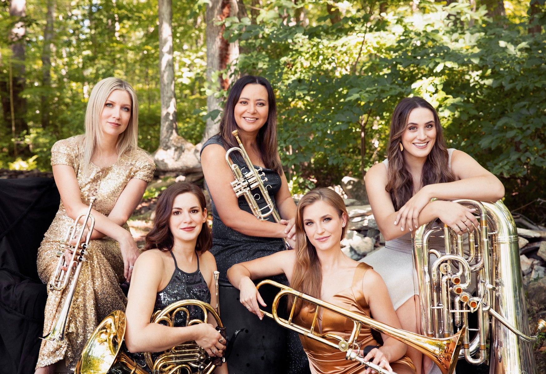 Five musicians pose outdoors with their brass instruments