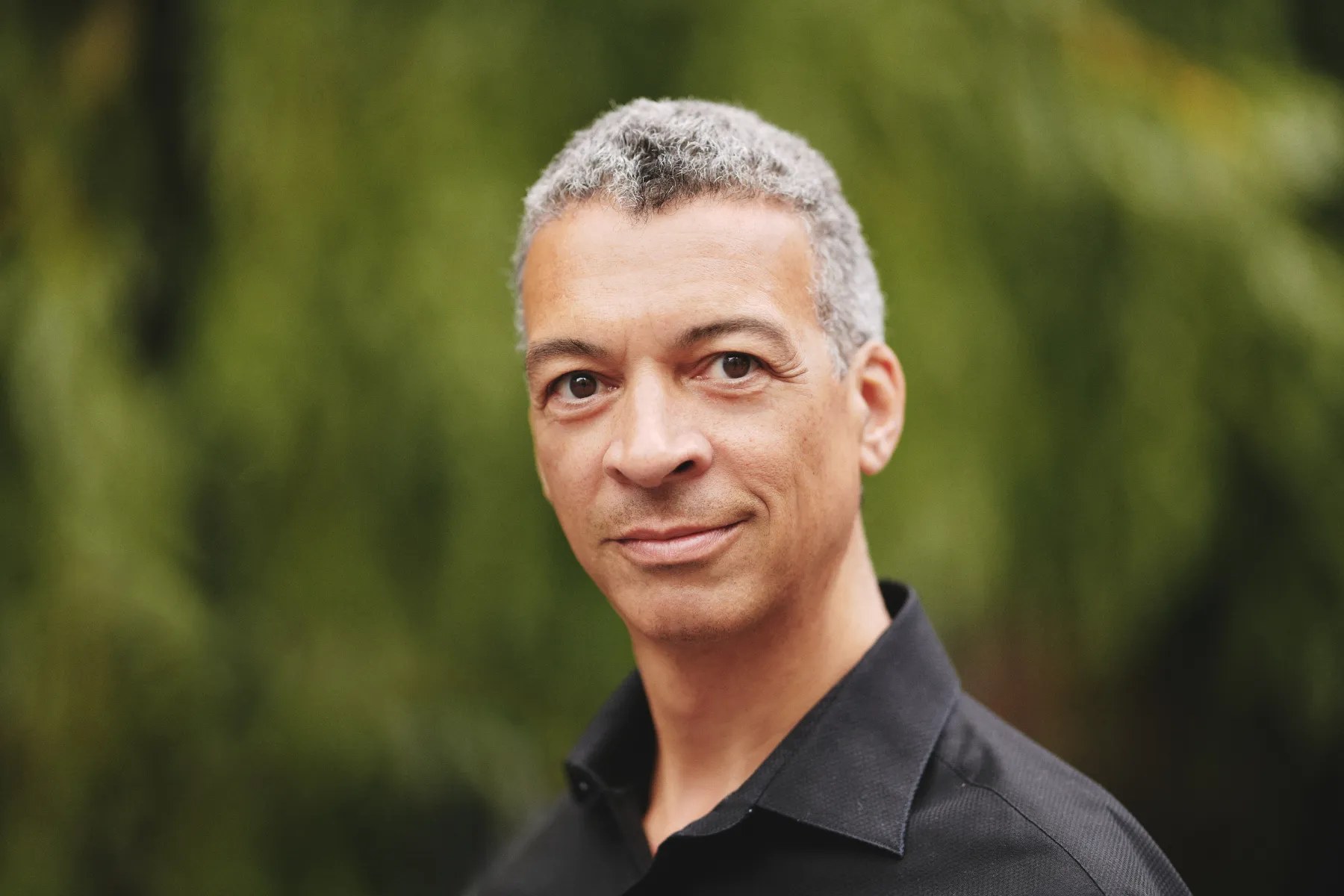 Roderick WIlliams smiling at the camera with a green nature background