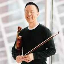David Kim holding a violin standing in front of a glass dome