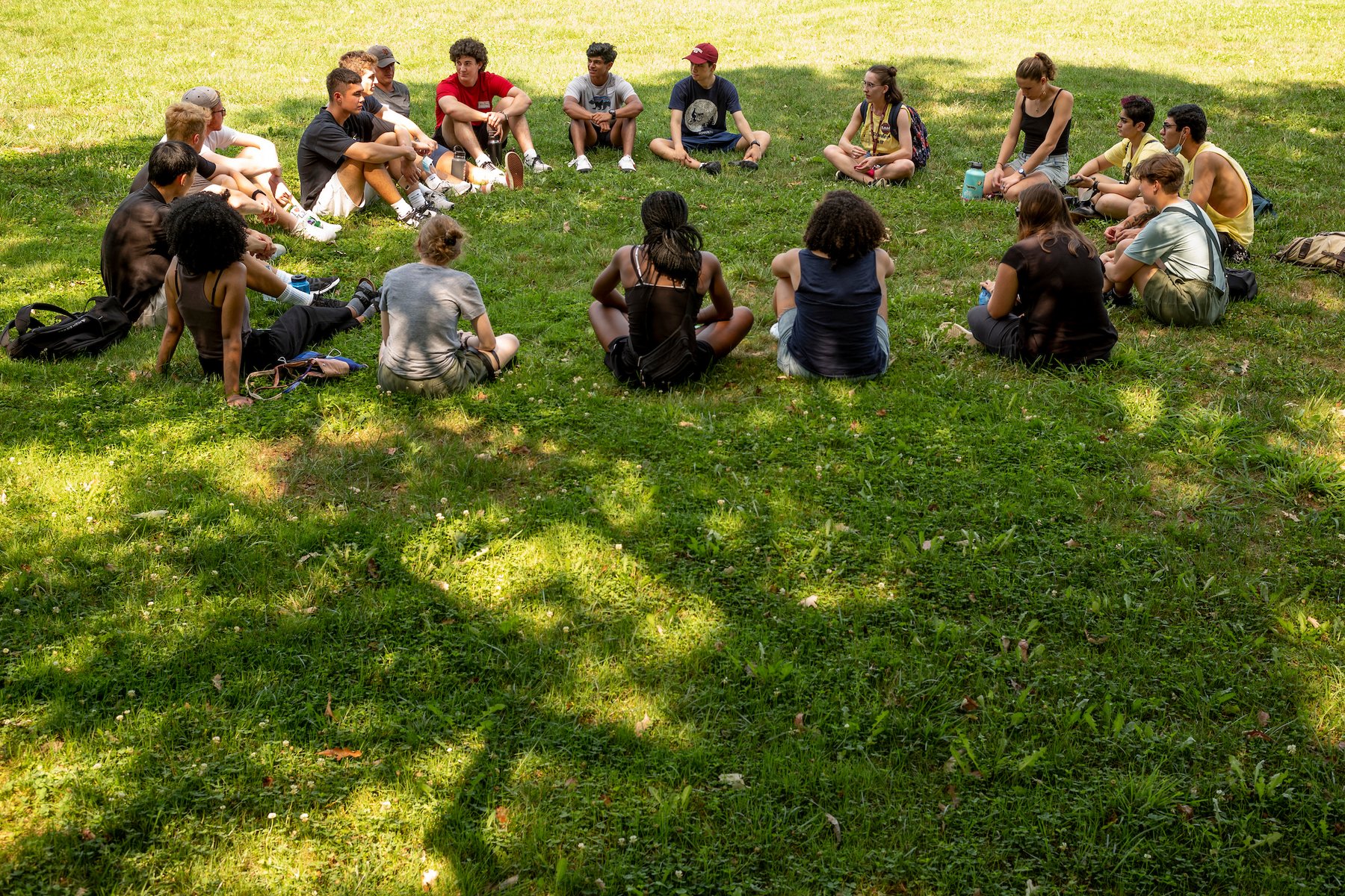 a group of students sitting in a circle on a grass lawn