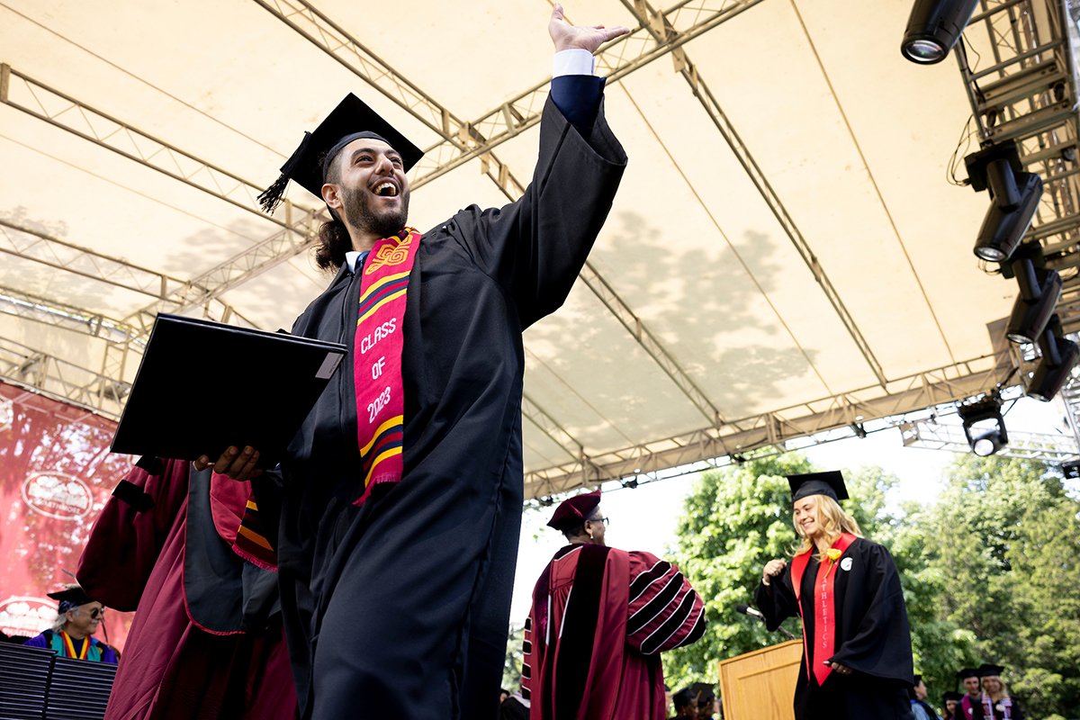 Person waves while receiving diploma
