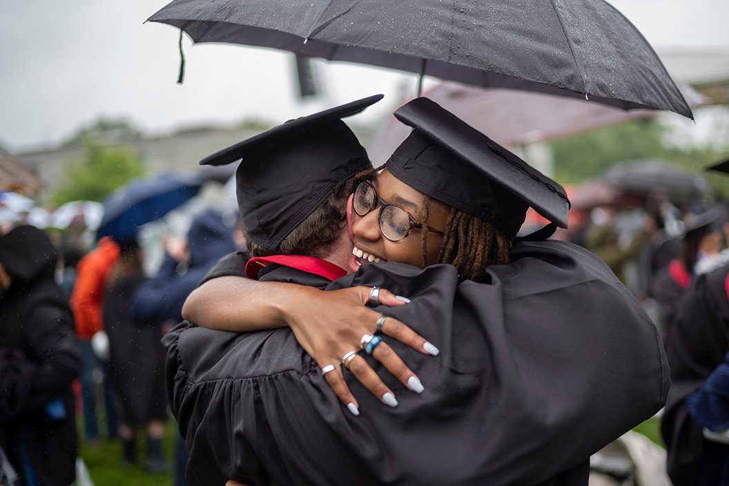Two people hug in cap and gowns