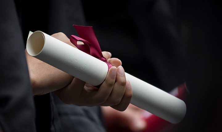 A hand holding a diploma at Commencement 2018