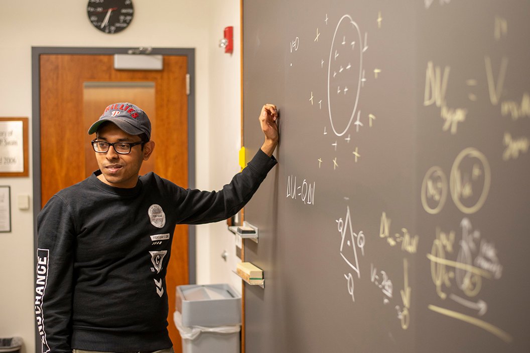 Tarzan Macmood '20 in front of chalkboard with math equations