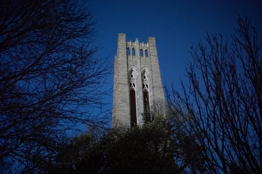 Clothier bell tower surrounded by branches against dark blue sky