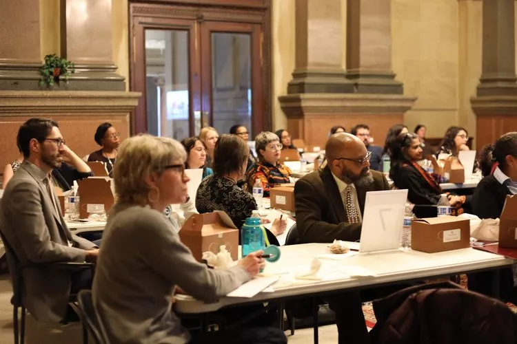 Participants seated at tables in City Hall