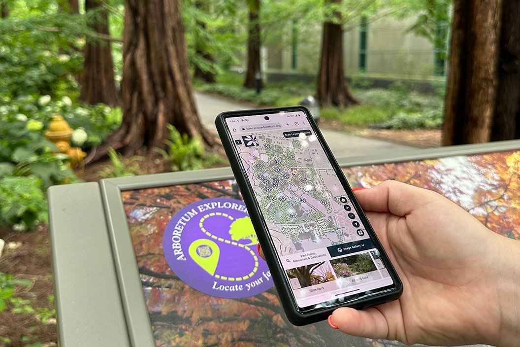 Person holding phone in hand looking at arboretum app