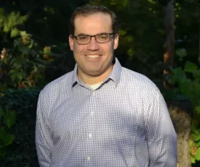 man in button down and glasses smiles at camera