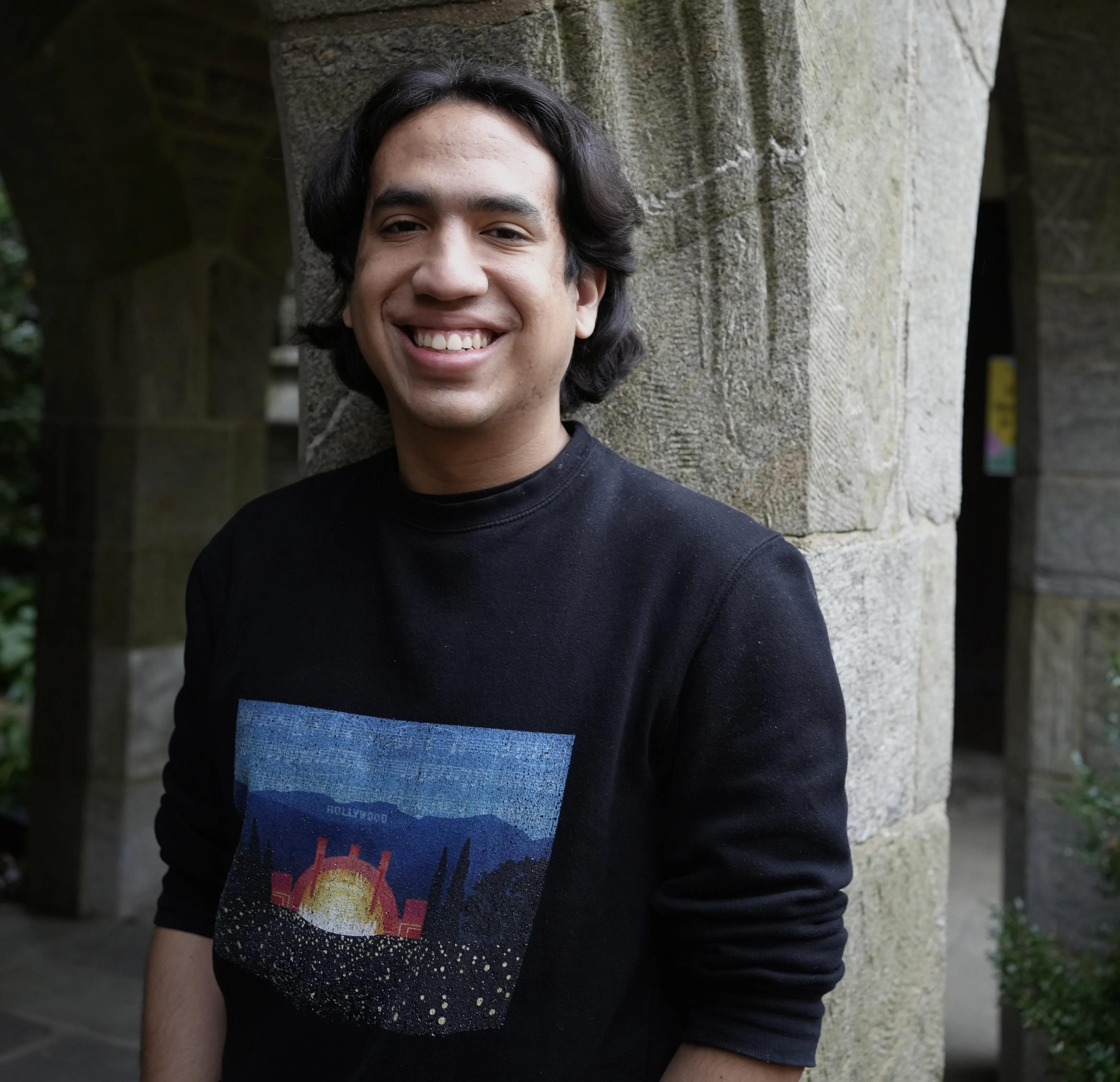 smiling Anthony Rumbos-Perez standing near in front of Clothier arch