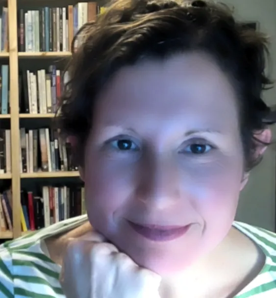 Photograph of Shannon Mattern leaning her head on her hand and seated in front of a bookcase