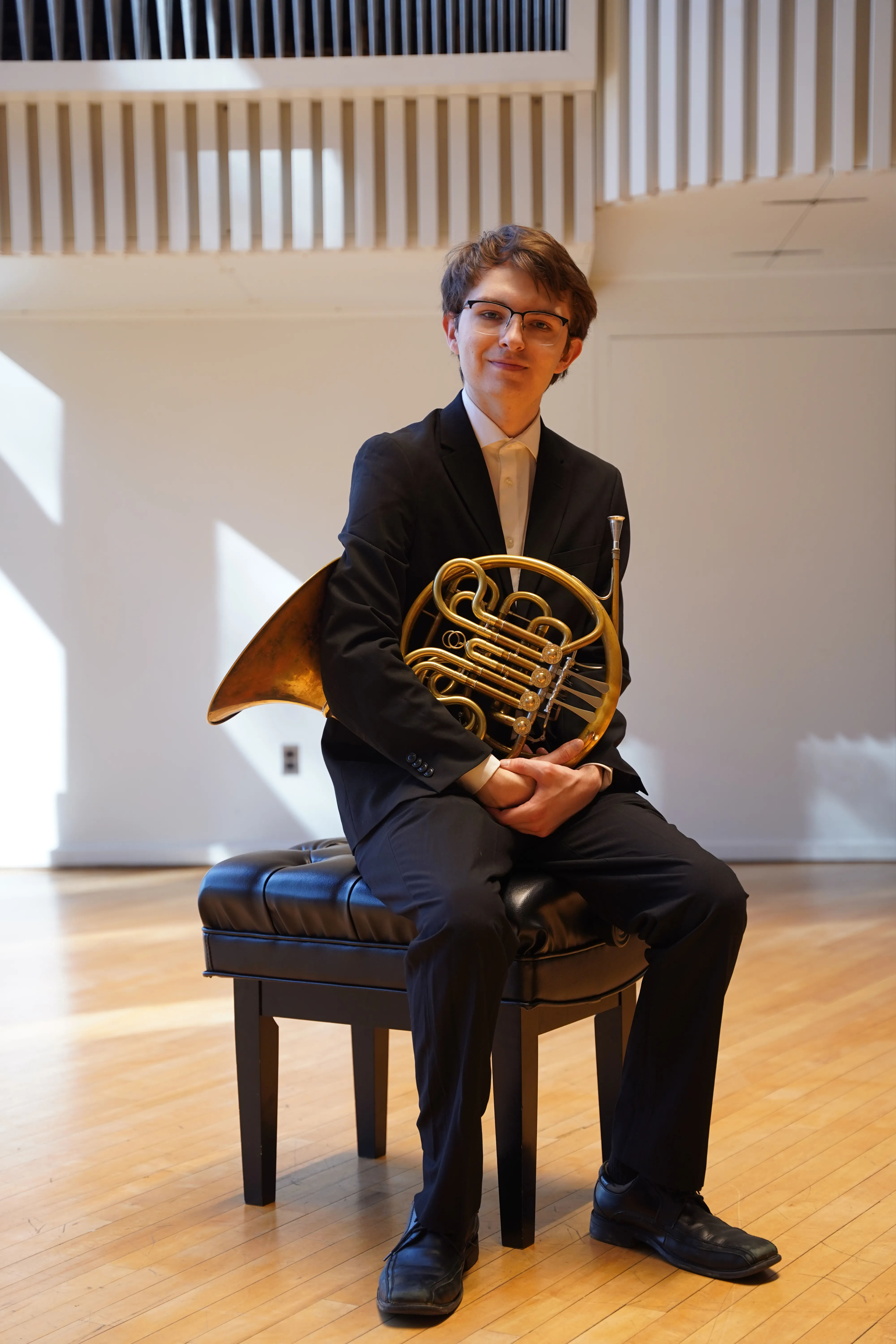 Duncan Wall '26 seated on the Lang Concert Hall stage with his french horn