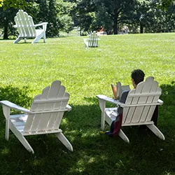 Person reads on white Adirondack chair on Parrish Beach