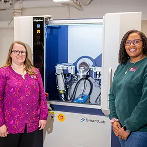 Hillary Smith and Kathryn Hiley in front of XRD machine