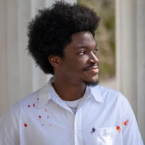 Steven Mukum ’26 stands in front of white pillars on patio of Parrish Hall