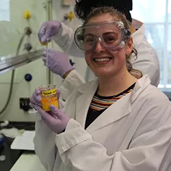 Student holds beaker with yellow chemical inside