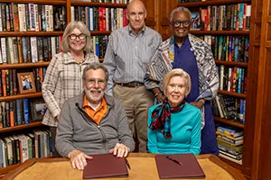Shankers at signing ceremony table with members of College leadership standing behind them