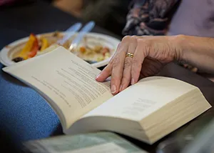 Person's hand turns pages of a book on a table