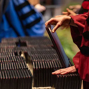 Stack of diplomas on table as unseen person sorts through them