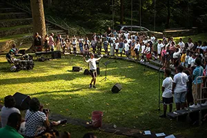 Person stands in outdoor amphitheater conducting choir