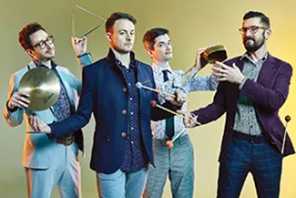 Group of four men pose while holding various percussion instruments